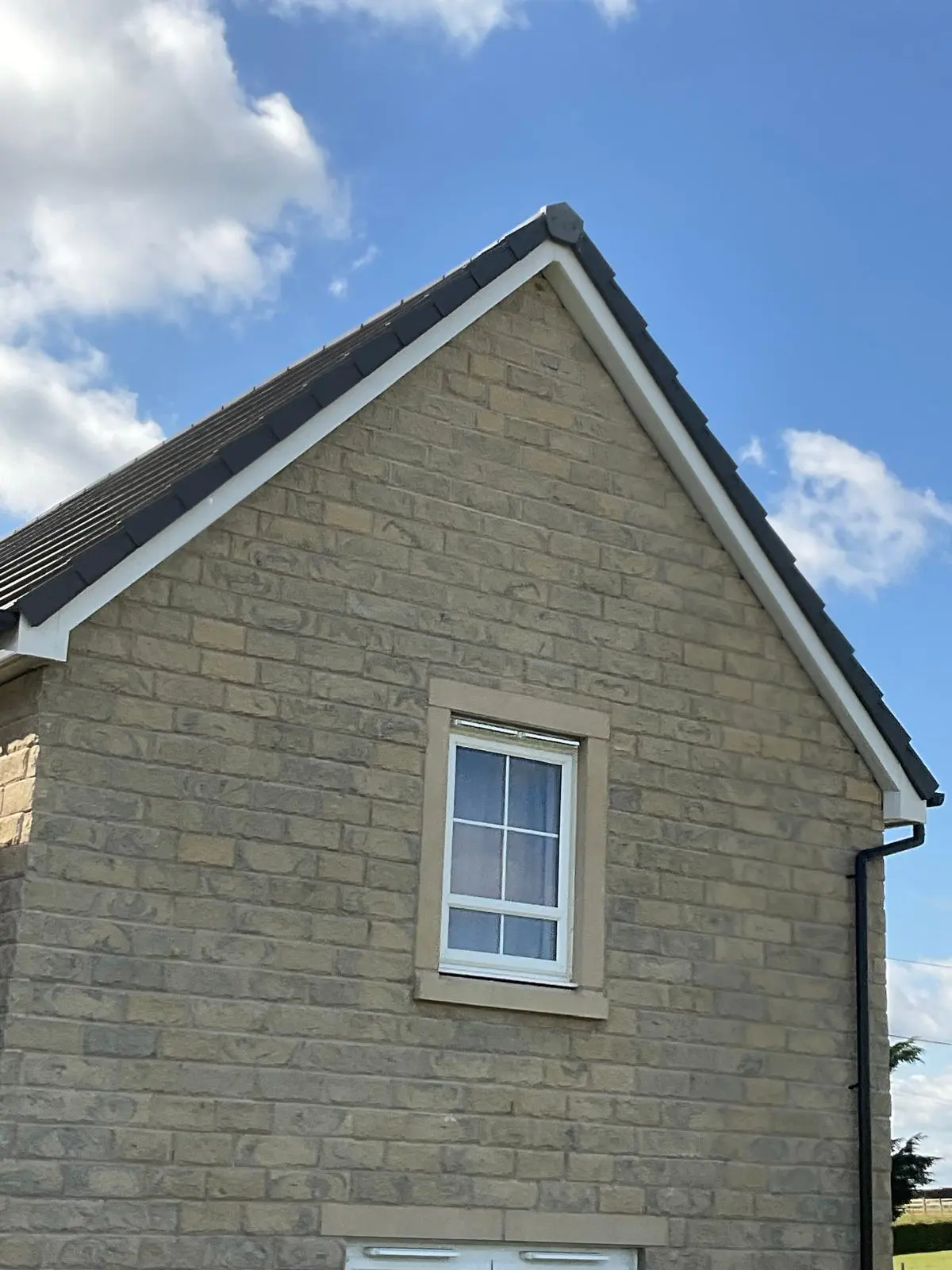 A newly installed pitched roof and white uPVC fascias on a stone house gable end