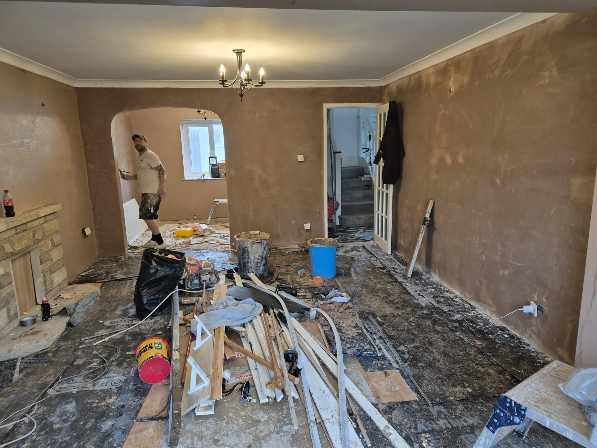 A domestic room under refurbishment with newly plastered walls and construction materials on the floor.