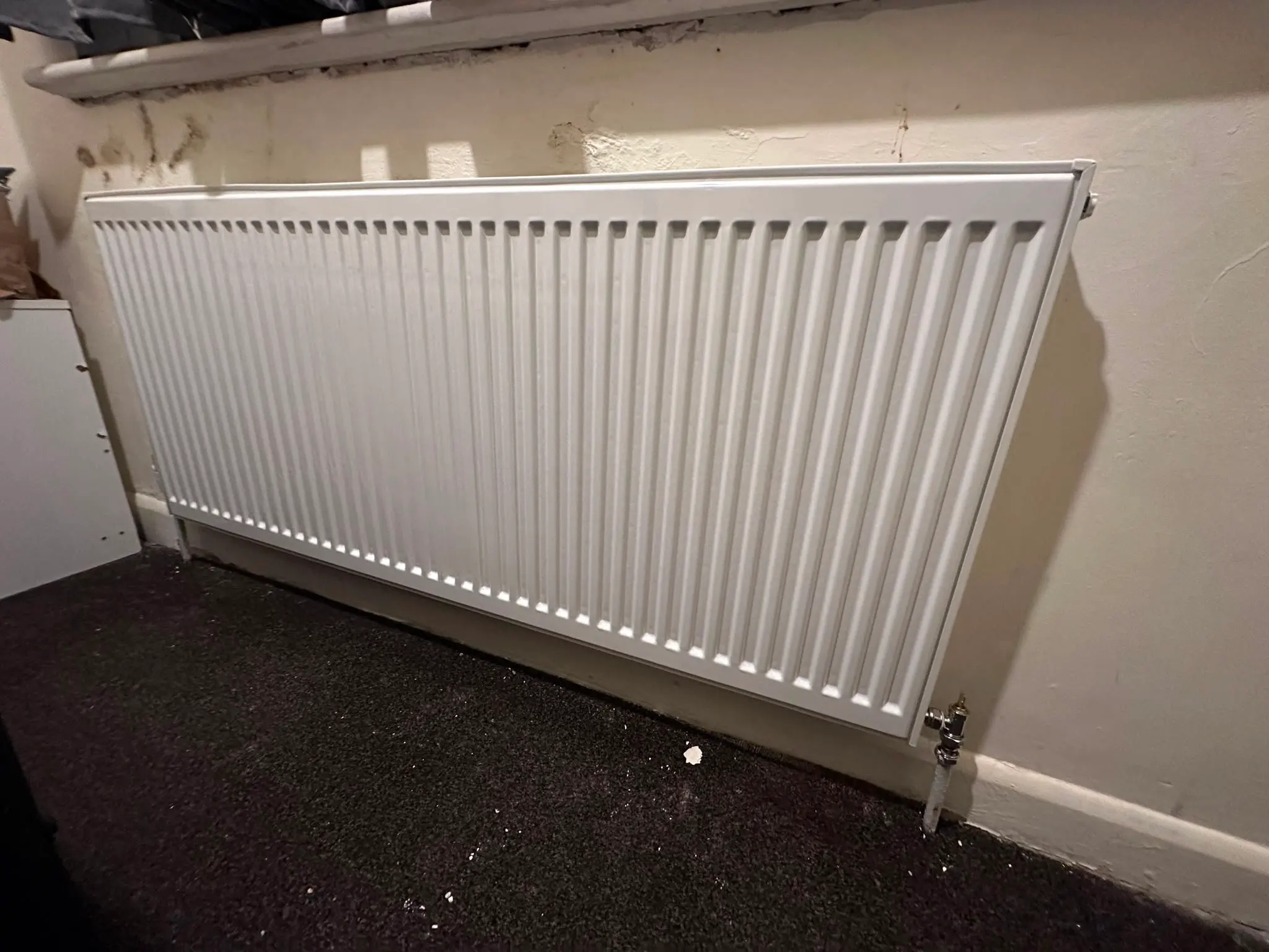 A white double panel radiator installed on a wall.