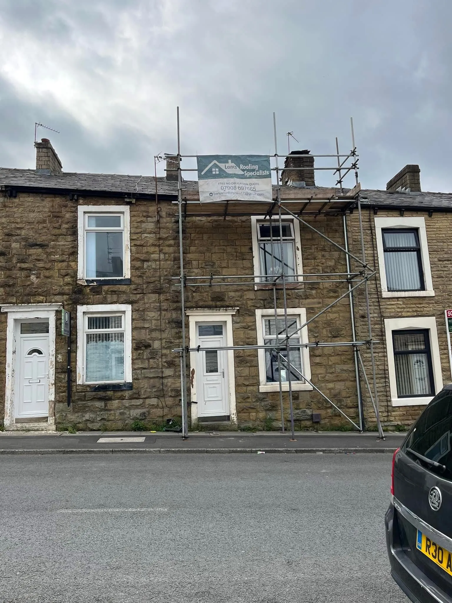 Lancashire Roofing Specialist scaffolding on a traditional stone terraced house in Blackburn during a roof replacement project.