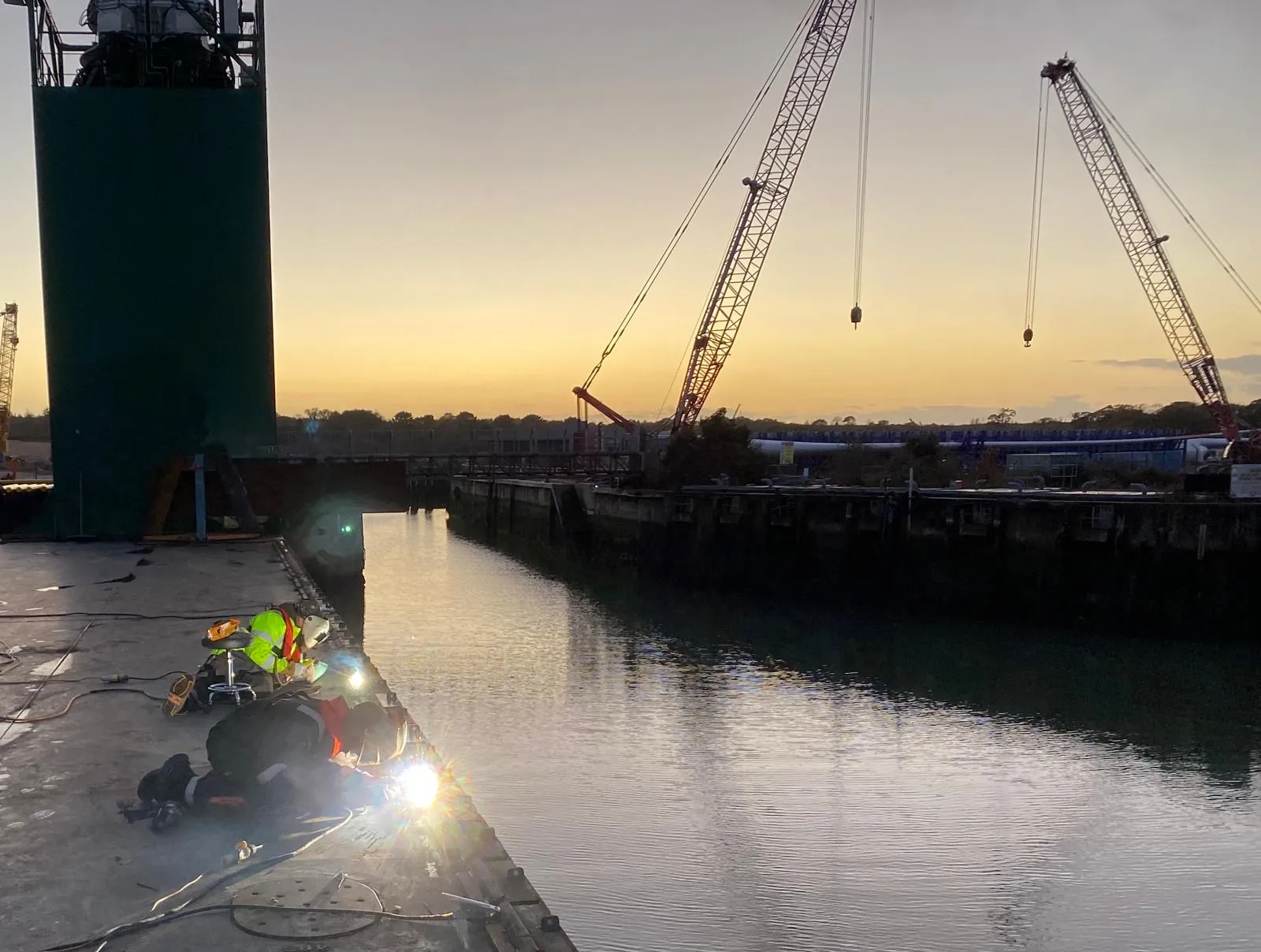 Coded welders carrying out marine repairs and steel fabrication at a dockside in Southampton.