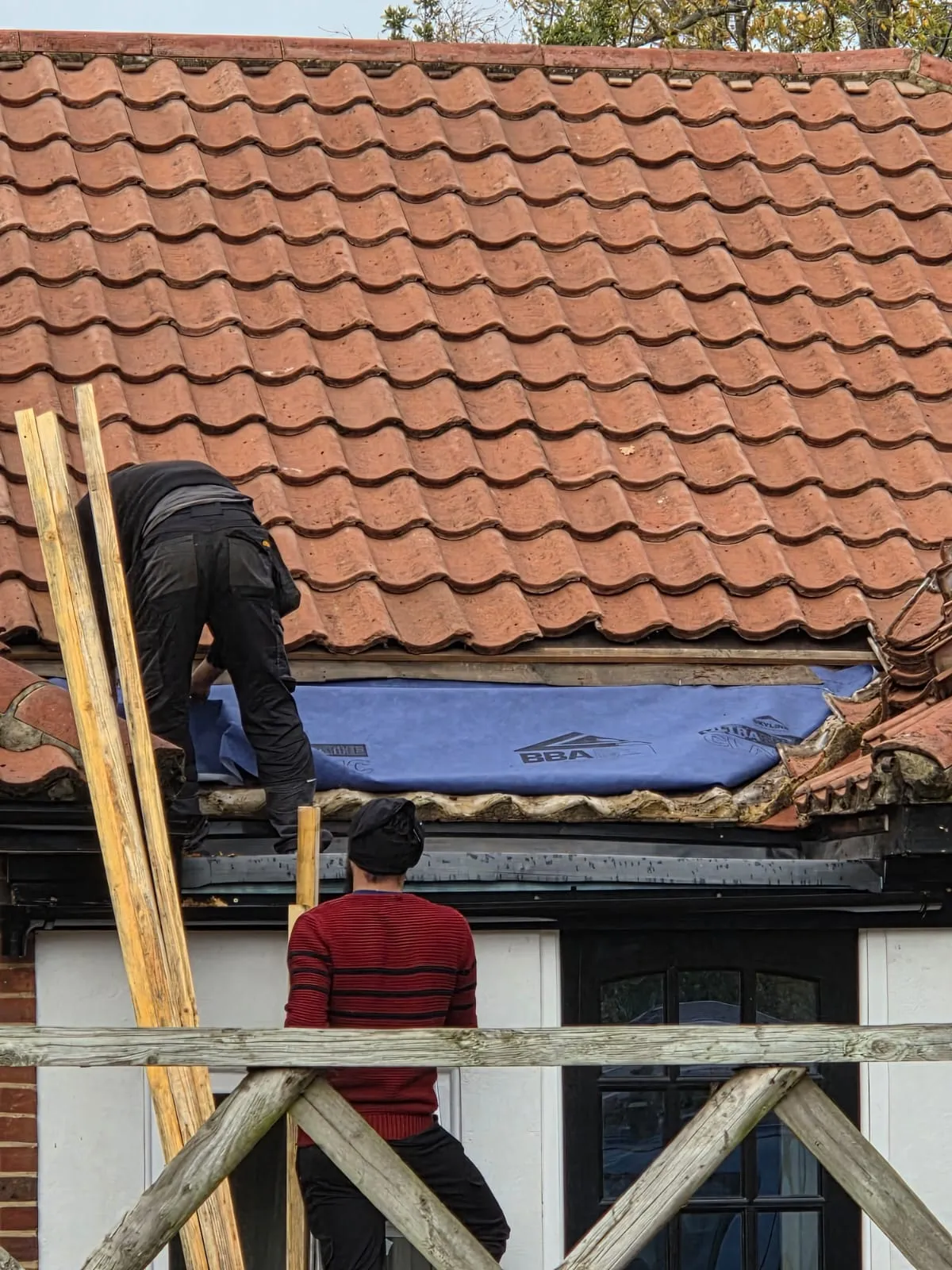 Local roofers in Cornwall installing breathable membrane and clay tiles during a roof repair.