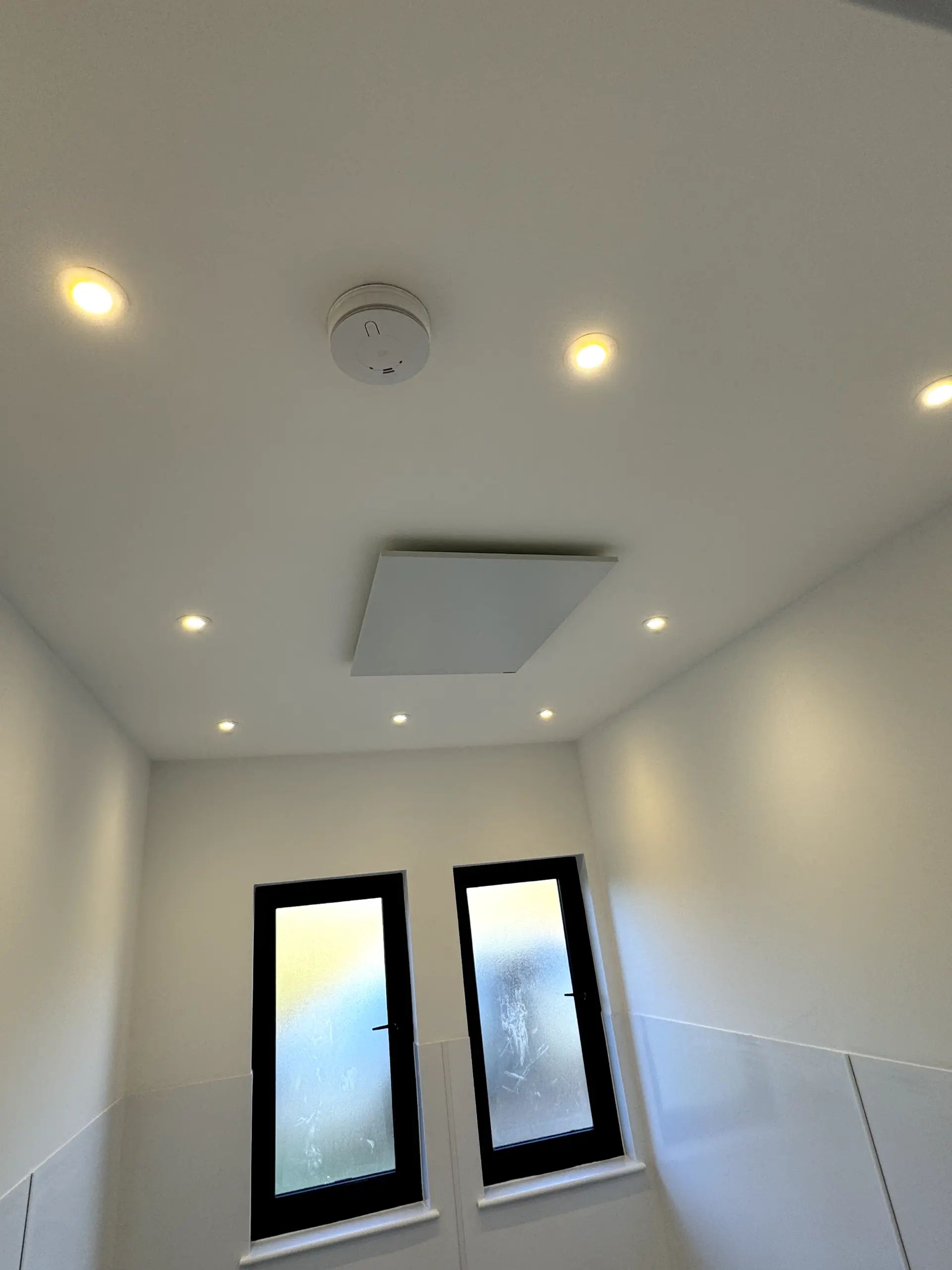 Newly installed LED spotlights and a smoke alarm on a white ceiling by JH Electrical Contractors Ltd