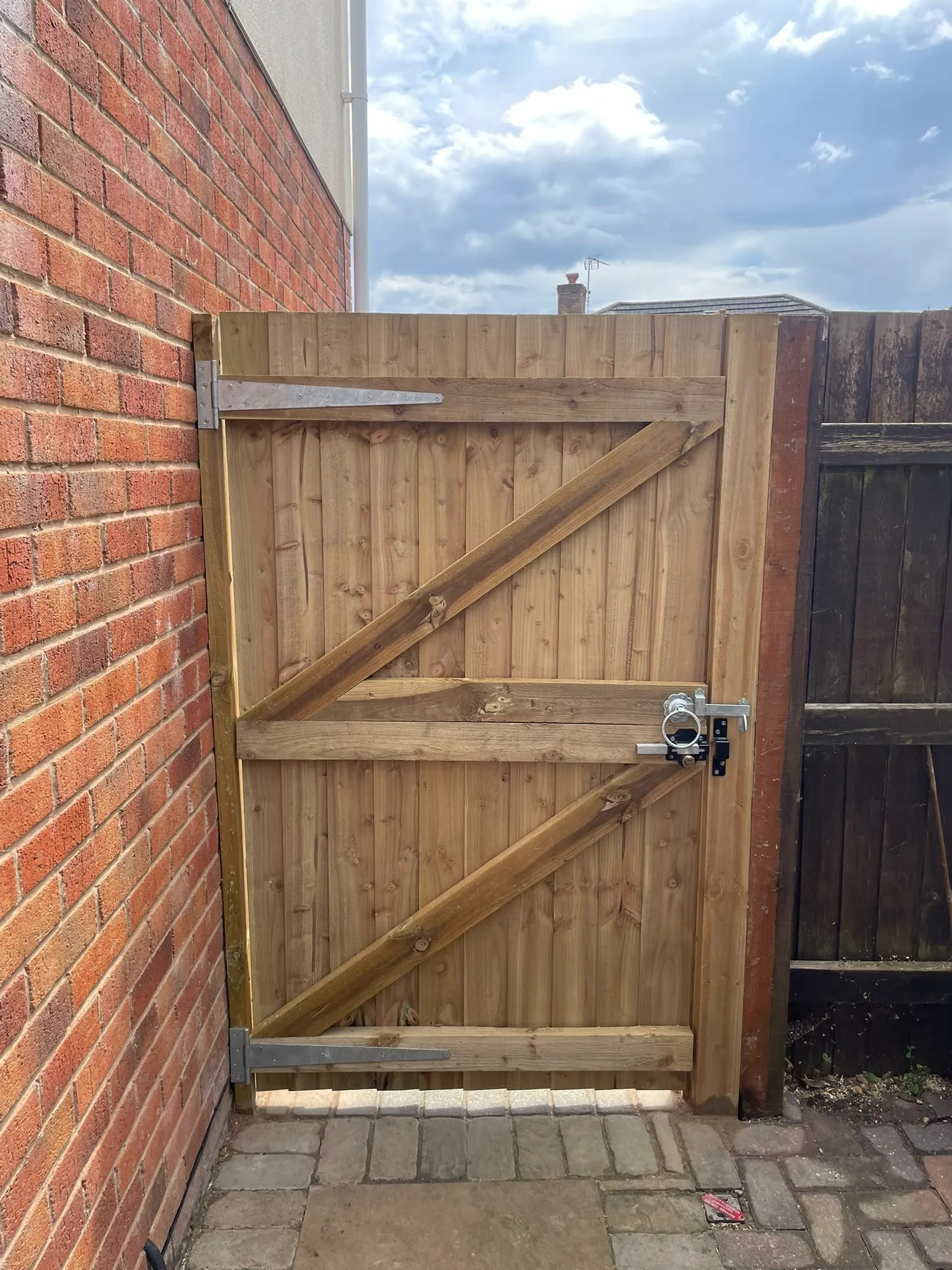Custom timber garden side gate installed between a brick house wall and boundary fence in Pontypool