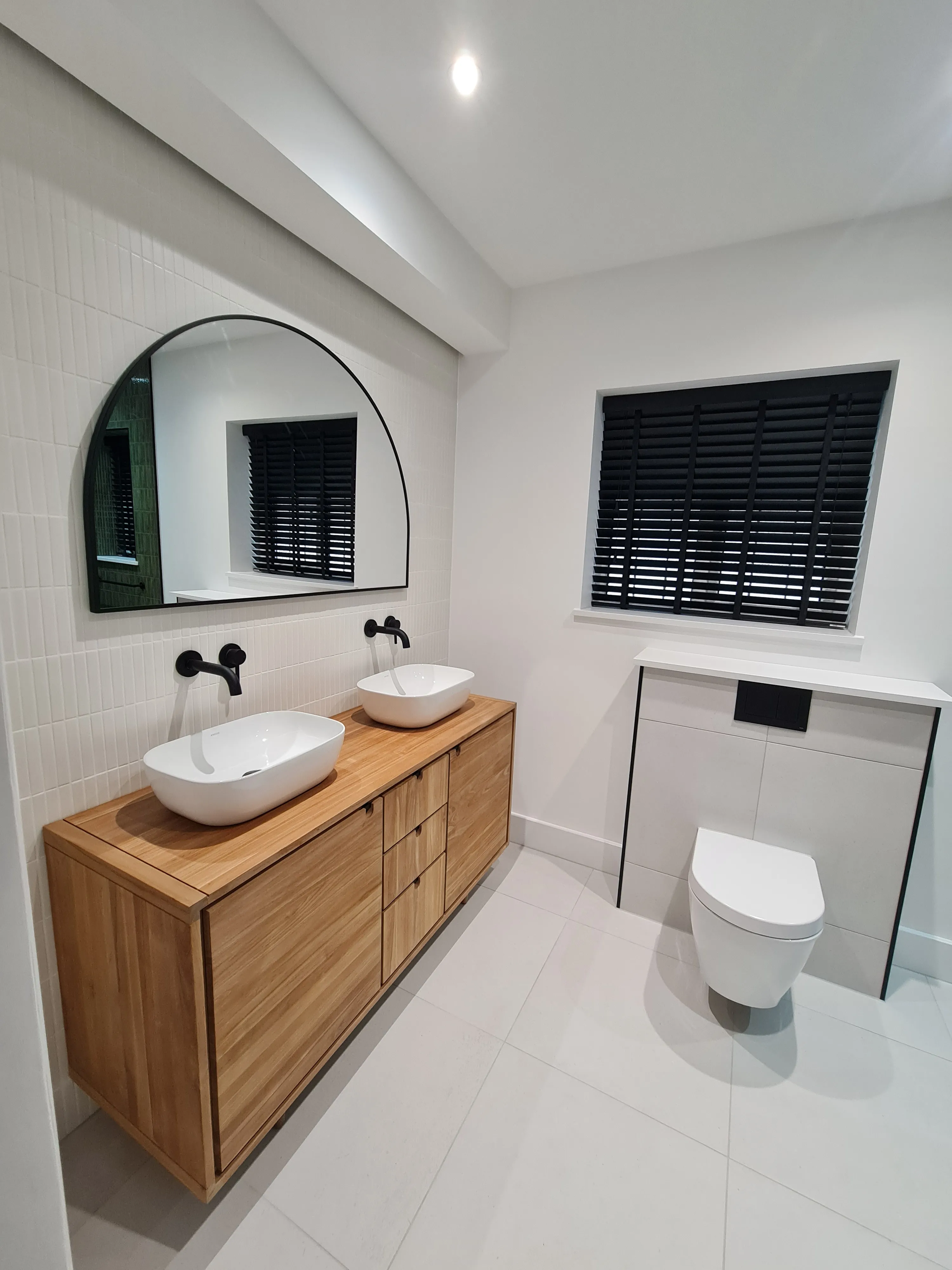 Bespoke master bathroom installation in Plymouth featuring a wood vanity and matte black fixtures by Sands & Vossen.