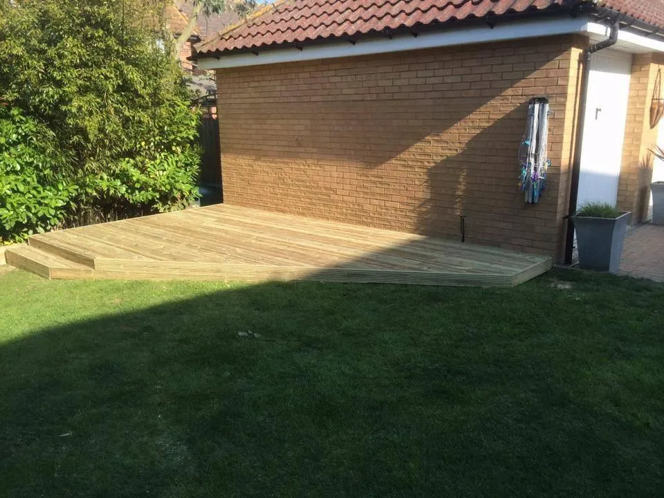 A picture of a newly installed timber deck with steps in a sunny garden