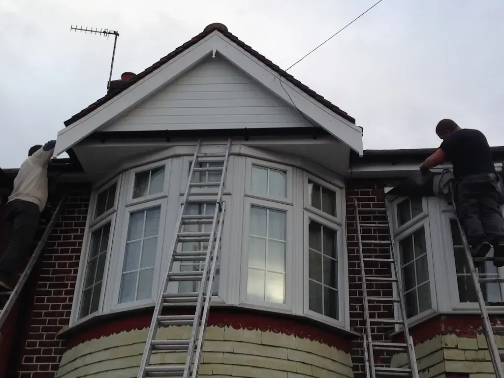 Workers installing or repairing fascias and soffits on a house roofline.