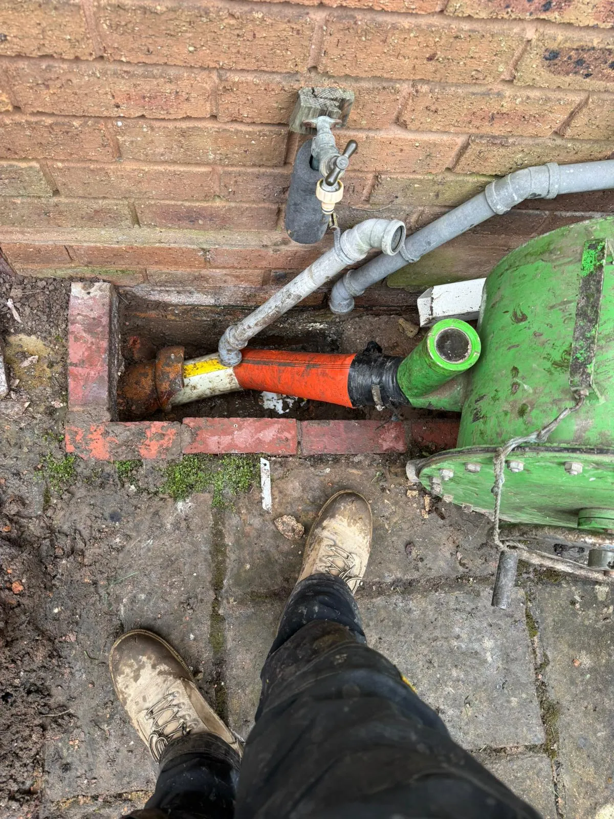 Drainage engineer installing a no-dig drain liner in a residential garden.