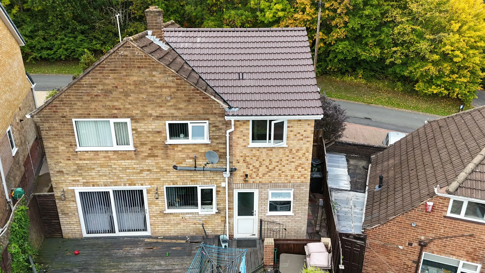 Aerial view of the back and side of a brick house with a decking area, showing space for a home extension.