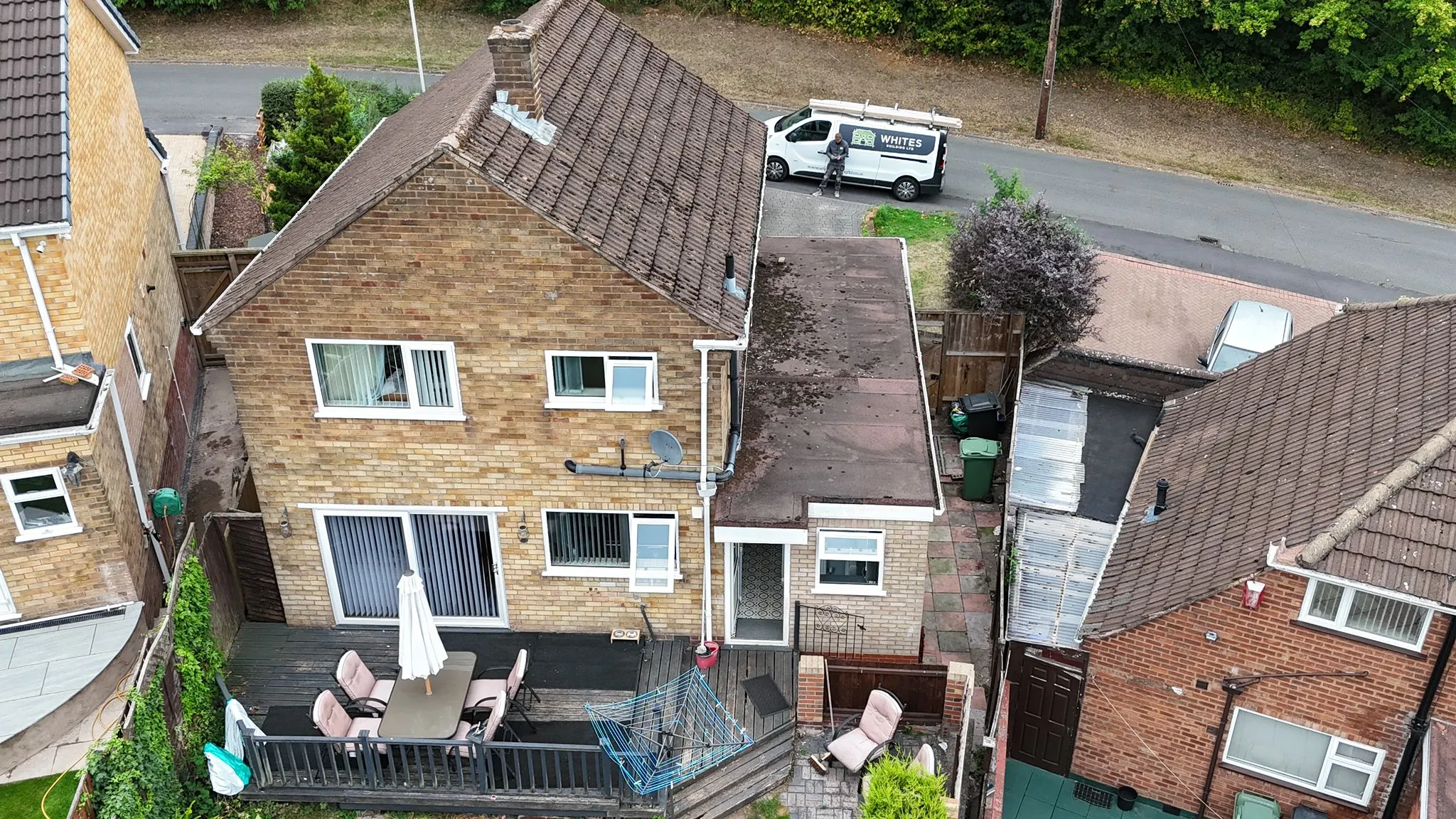 Aerial view of a house with an existing extension, showing the roof, garden, and a Whites Building LTD van.