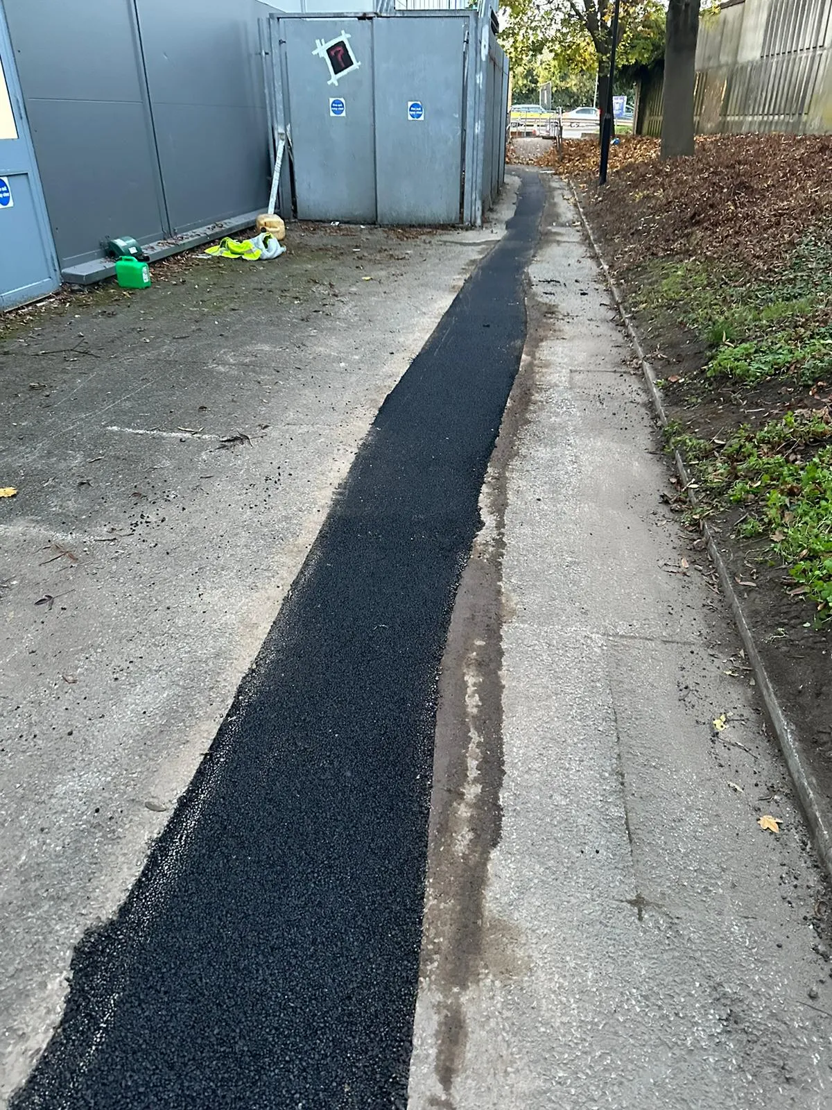 Fresh tarmac reinstatement over a completed trench for drainage repairs or civil engineering.