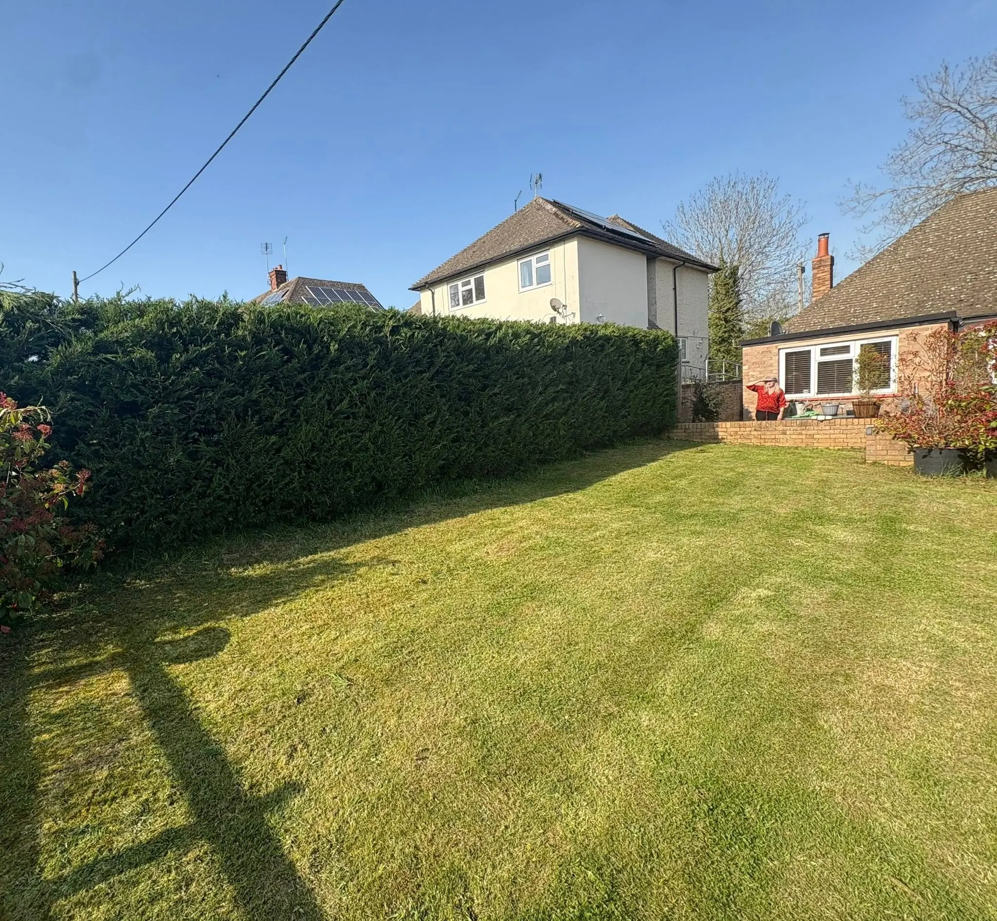 A neatly cut hedge and lawn in a residential garden, demonstrating grounds maintenance services
