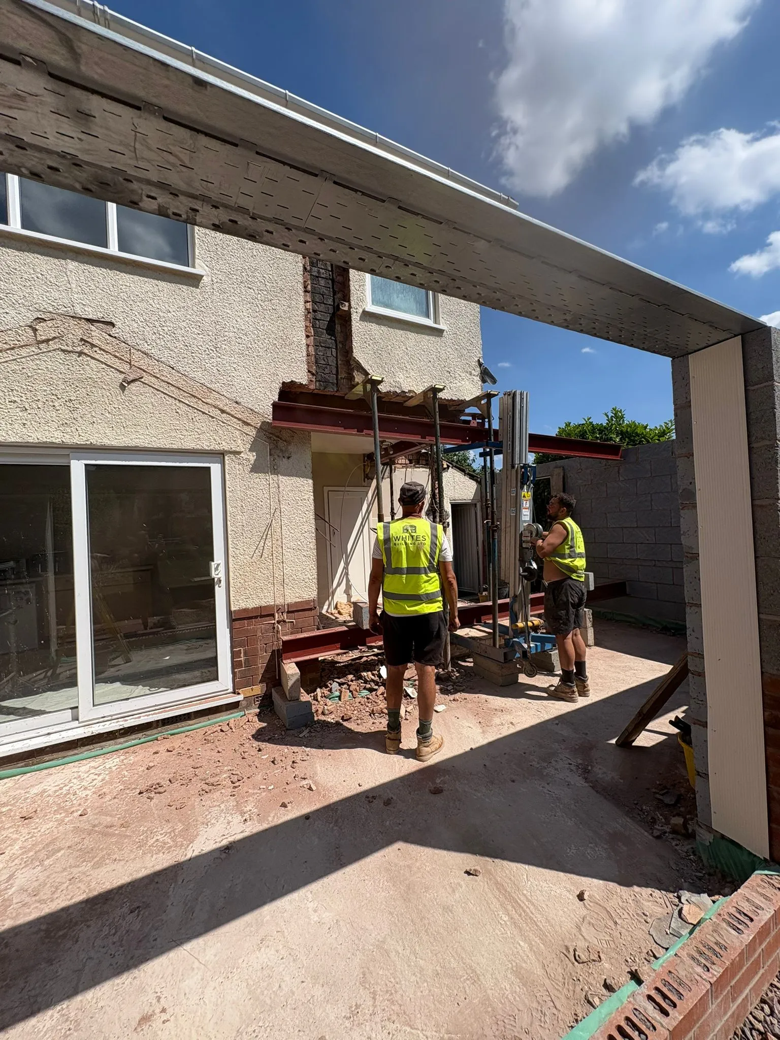 Two skilled builders from Whites Building Ltd installing steel beams on a construction site.