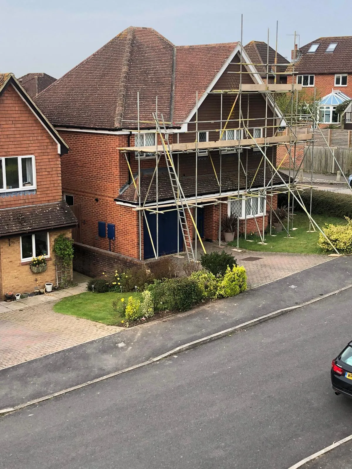 A residential property with a tiled roof, surrounded by scaffolding for ongoing or upcoming roofing and external property maintenance services.