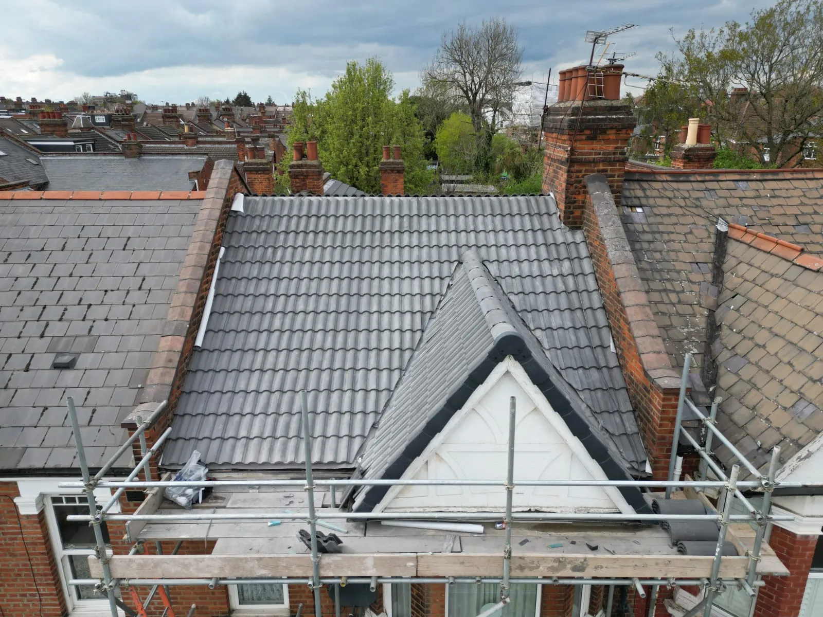 Newly fitted grey tiled roof with a dormer window and scaffolding on a residential building.