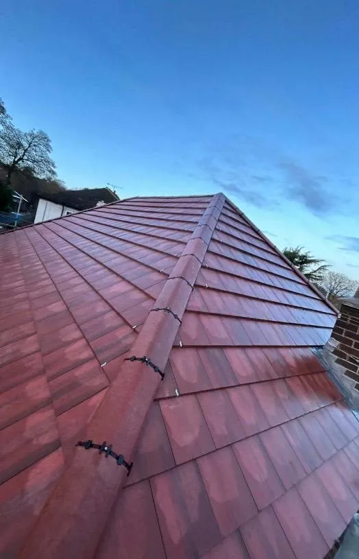 A close-up view of a professionally installed red tile roof with a dry fix hip system.
