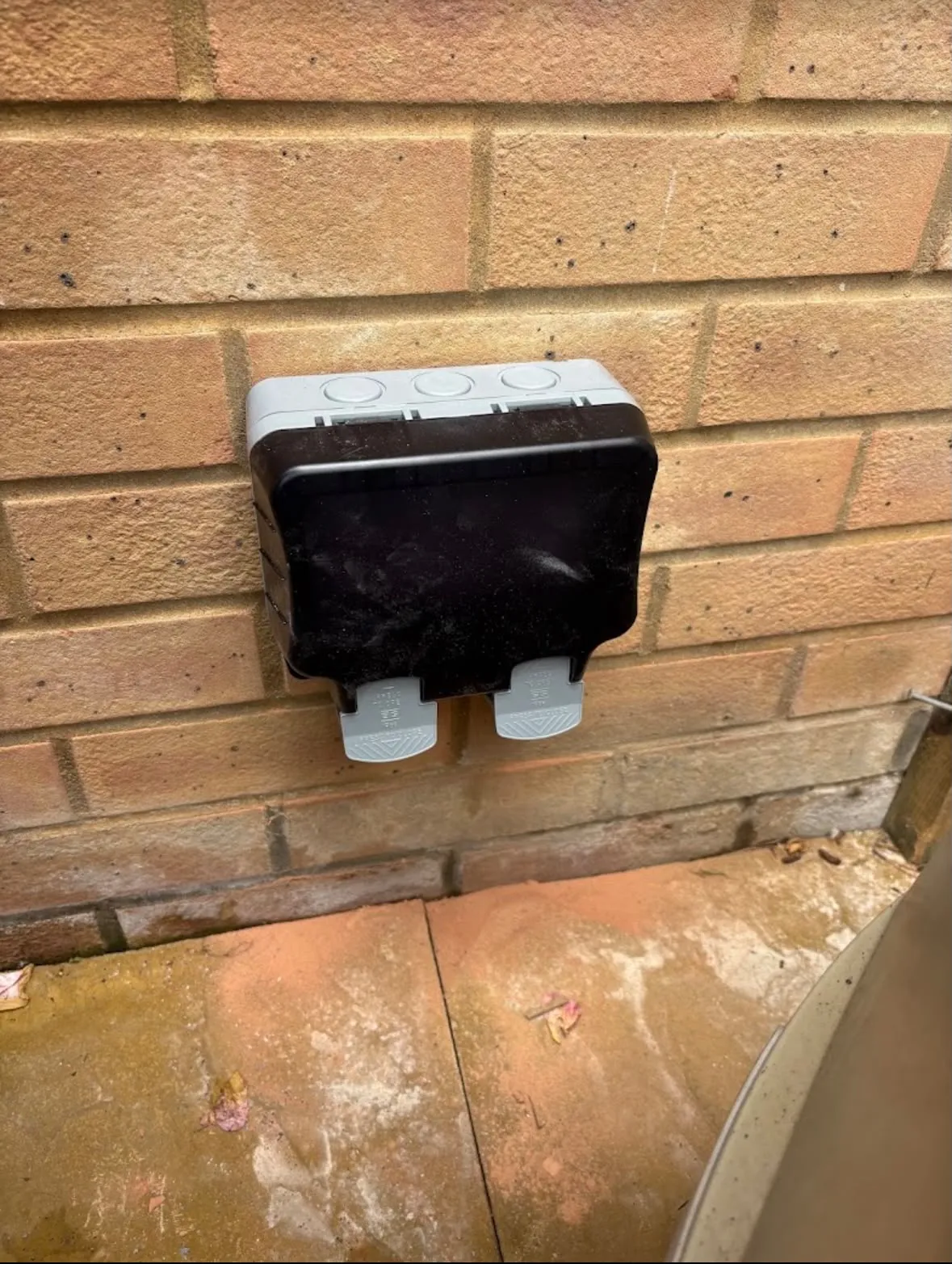 Weatherproof outdoor double socket installation on an exterior brick wall