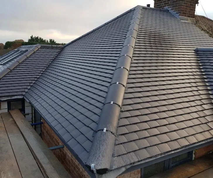 A newly installed grey tiled roof on a residential property, showcasing modern roofing techniques and a dry ridge system.