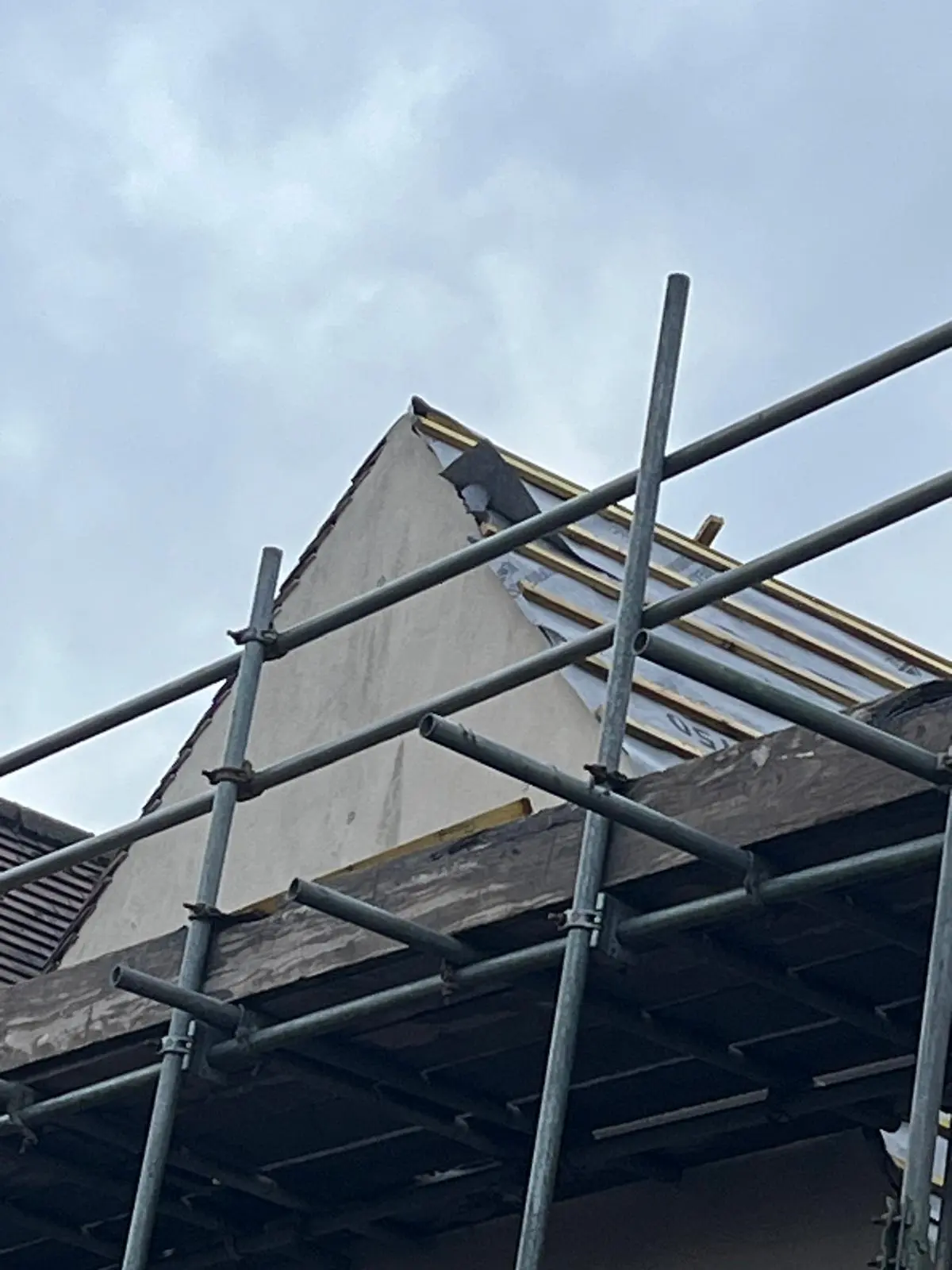 Pitched roof replacement in progress with scaffolding and timber battens visible