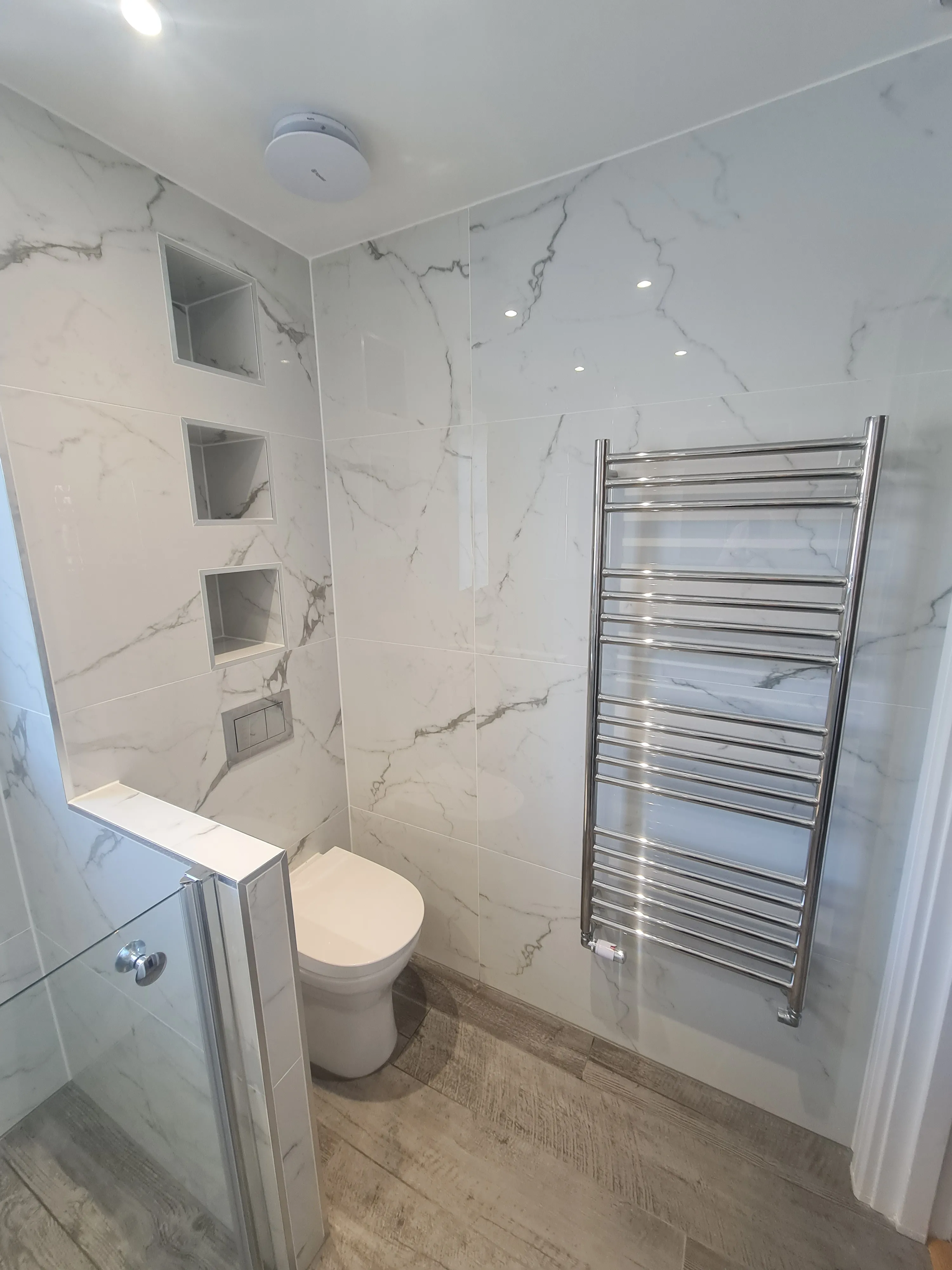 Luxury bathroom installation in Plymouth featuring marble tiling and bespoke recessed niches by Sands & Vossen.