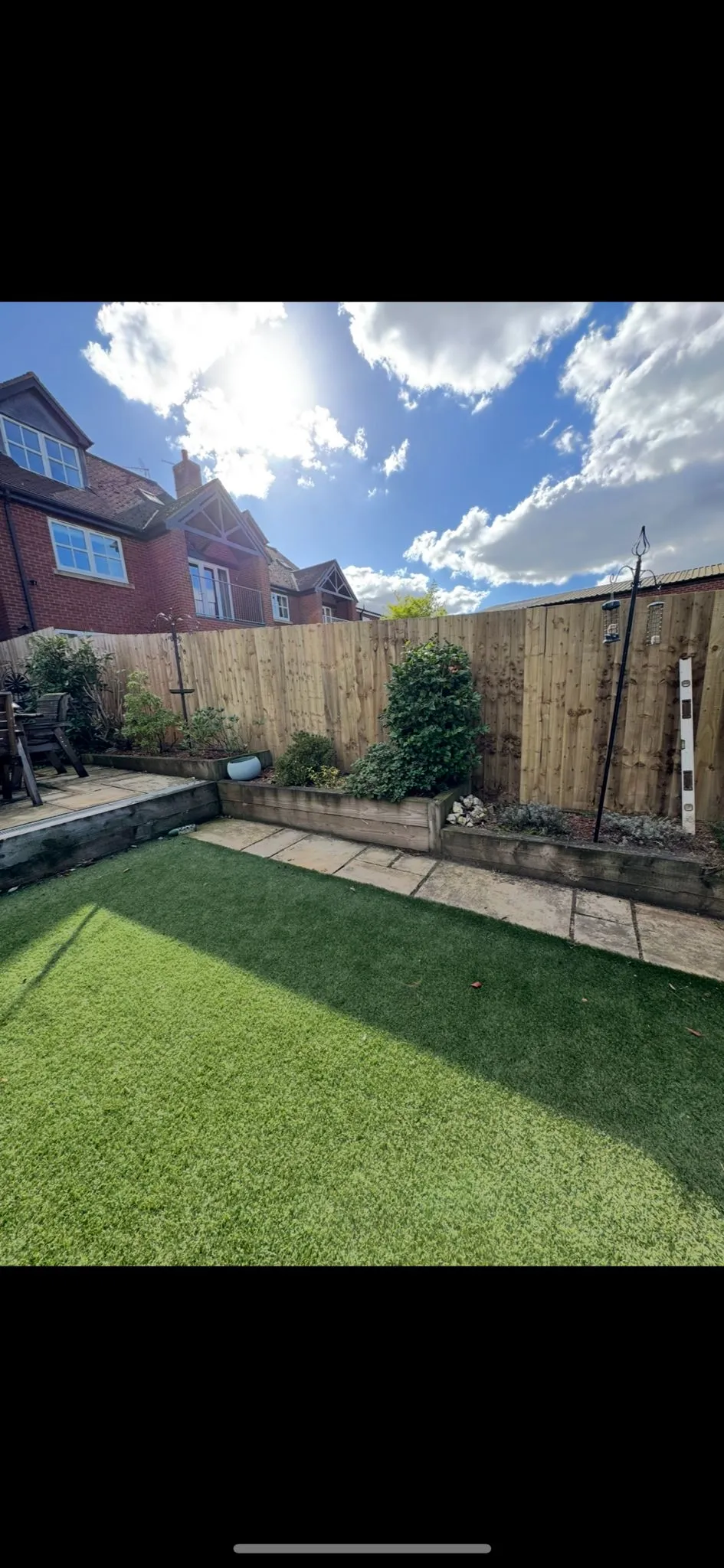Modern garden transformation with artificial lawn, raised timber planters, paved patio, and new closeboard fence in Leicestershire.