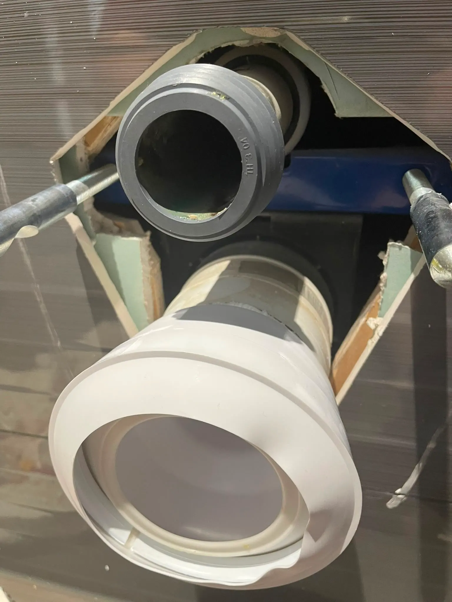 Plumbing pipes and mounting rods prepared for a wall-hung toilet installation