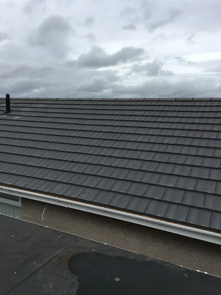 Modern grey tiled roof with white guttering on a house in Lanark