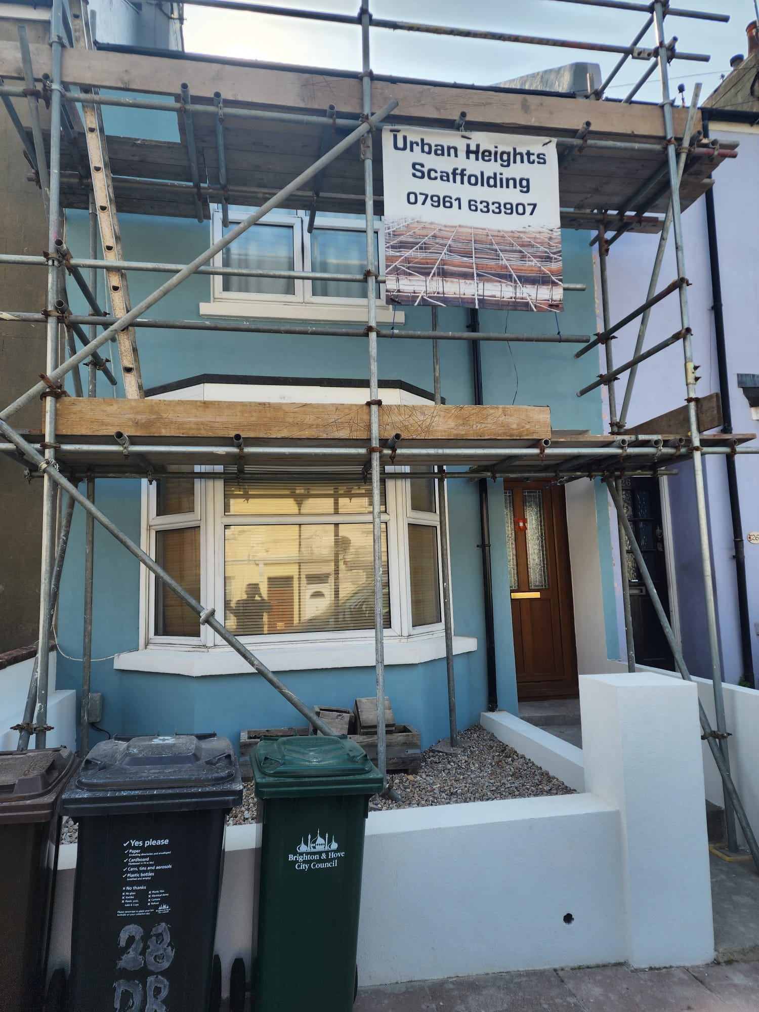 A house with a new light blue rendered finish and scaffolding, showcasing professional external rendering work by Portslade Plastering.