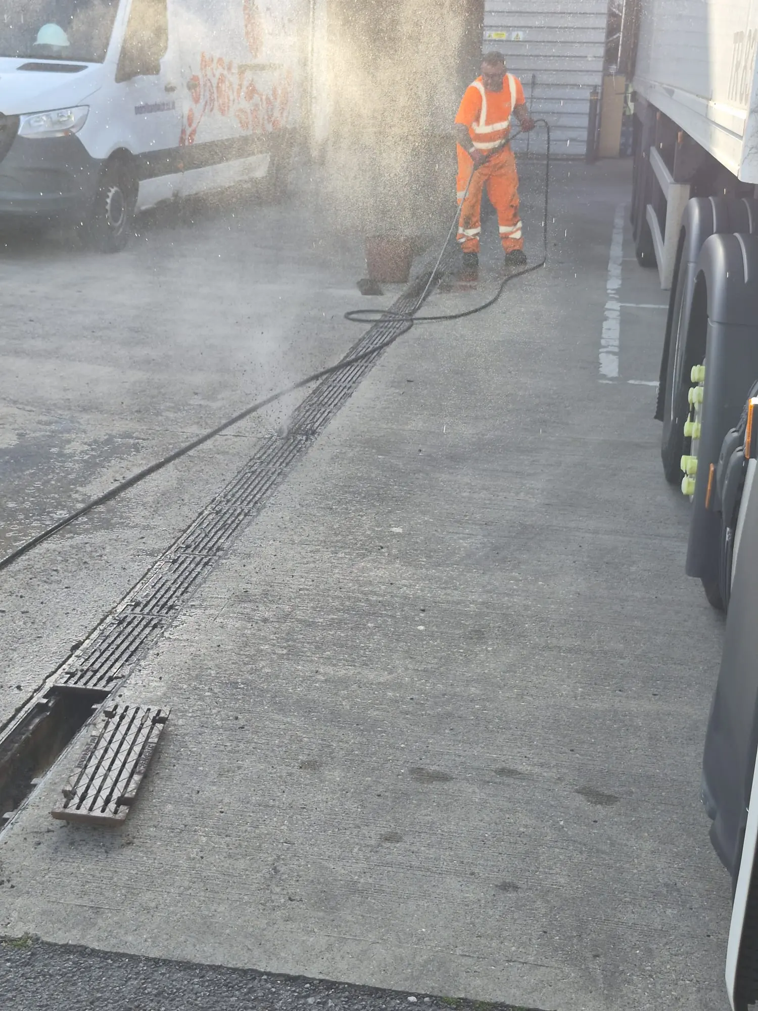 APJ Drainage engineer using high-pressure water jetting to clean a commercial grated trench drain.