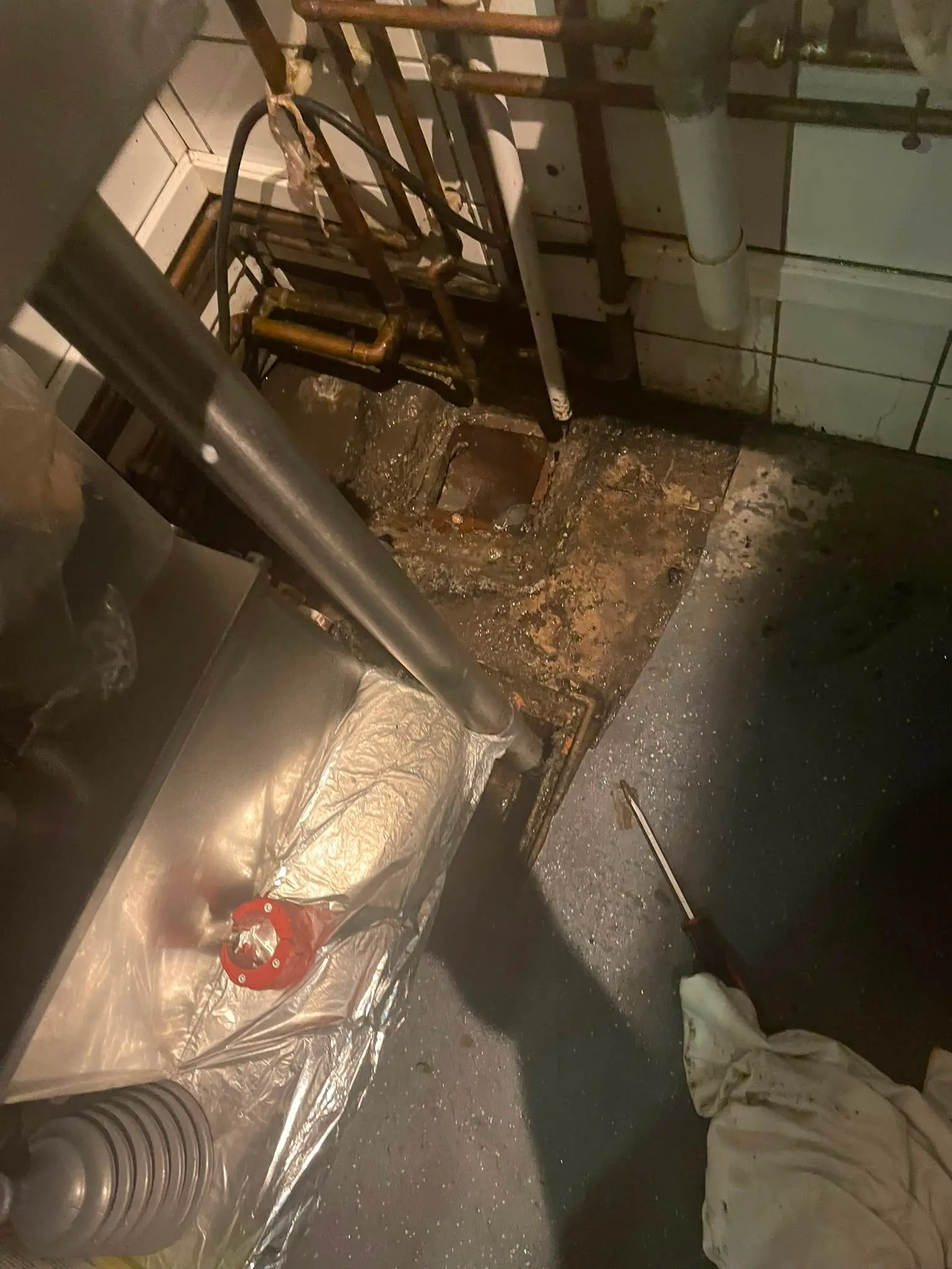 A blocked and overflowing floor drain with dark sludge