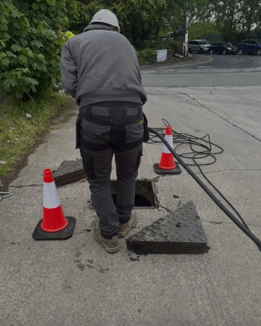 Fast Drainage Northwest commercial engineer working on manhole safely with cones
