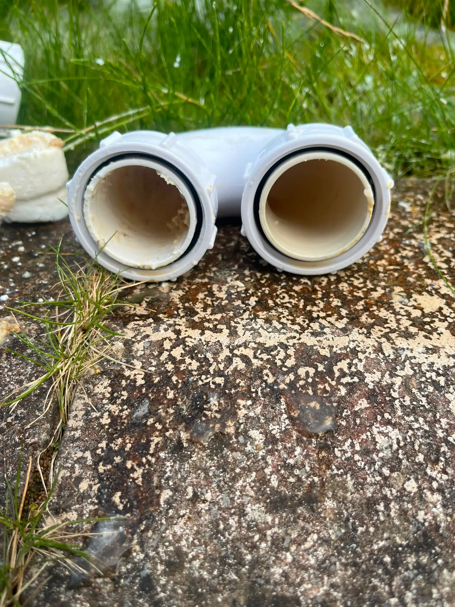 Removed white plastic drain pipe showing internal scale and fat build-up