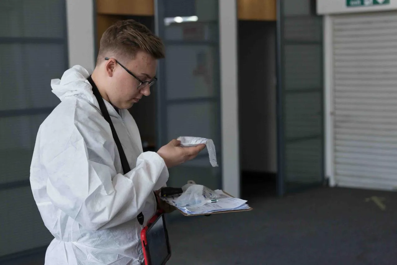 Asbestos surveyor in protective suit examining a sample or survey documents.