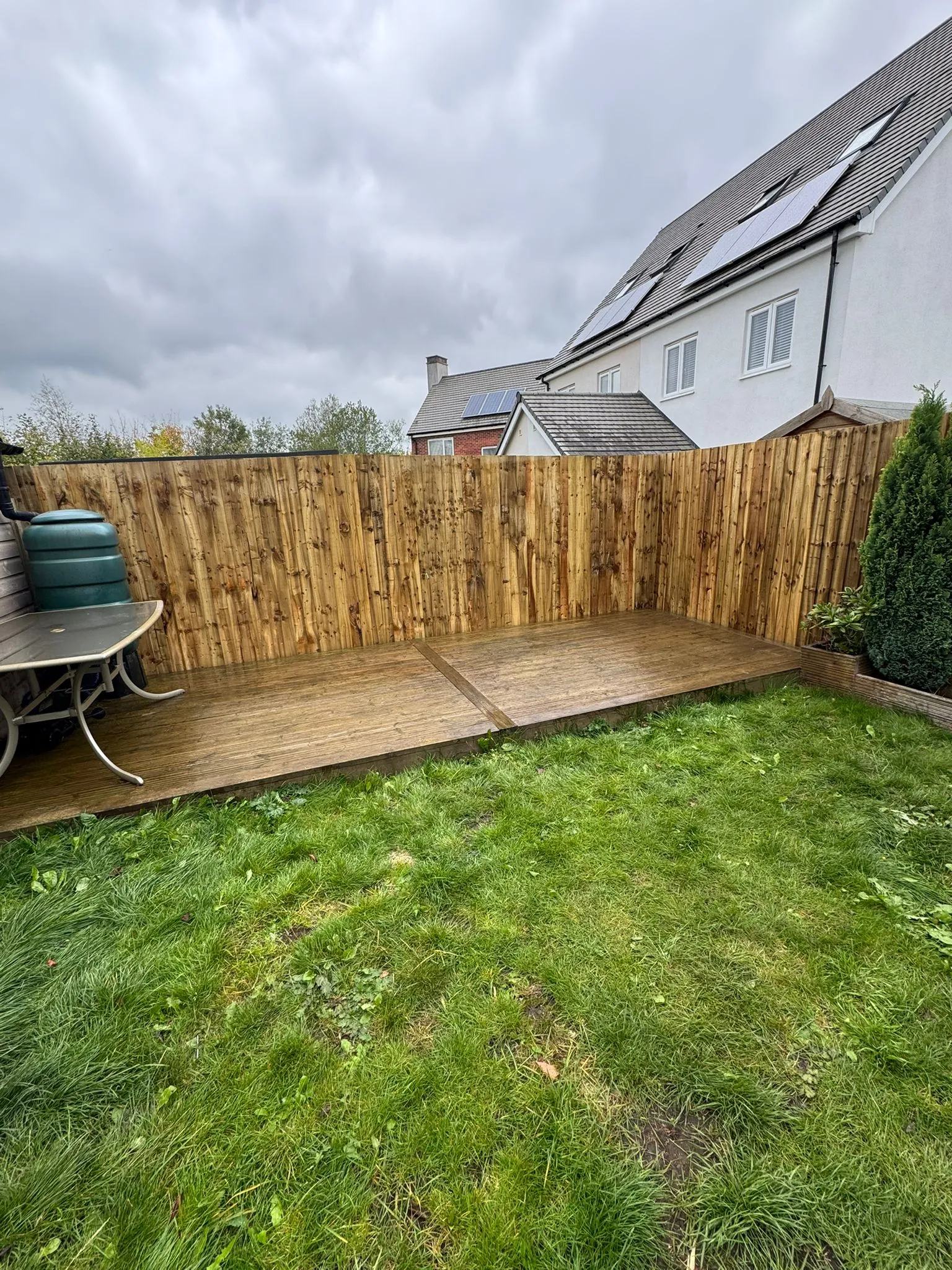 Newly installed timber decking and wooden closeboard fence in a residential garden.