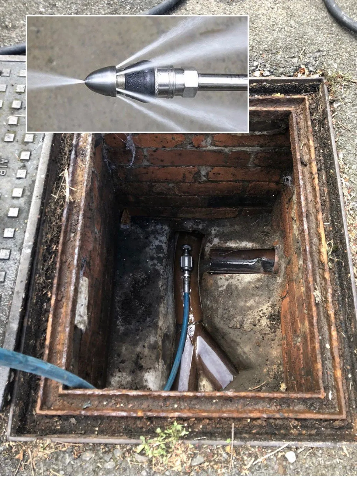 High-pressure water jetting equipment used for clearing blocked drains in a manhole.