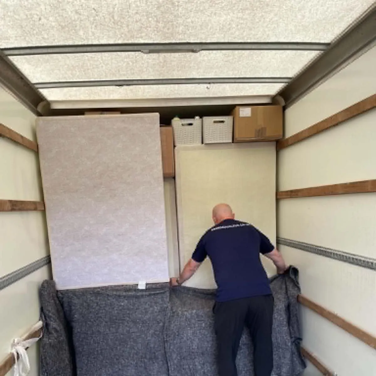 RM Removals mover packing and protecting furniture with heavy-duty transit blankets inside a removal van