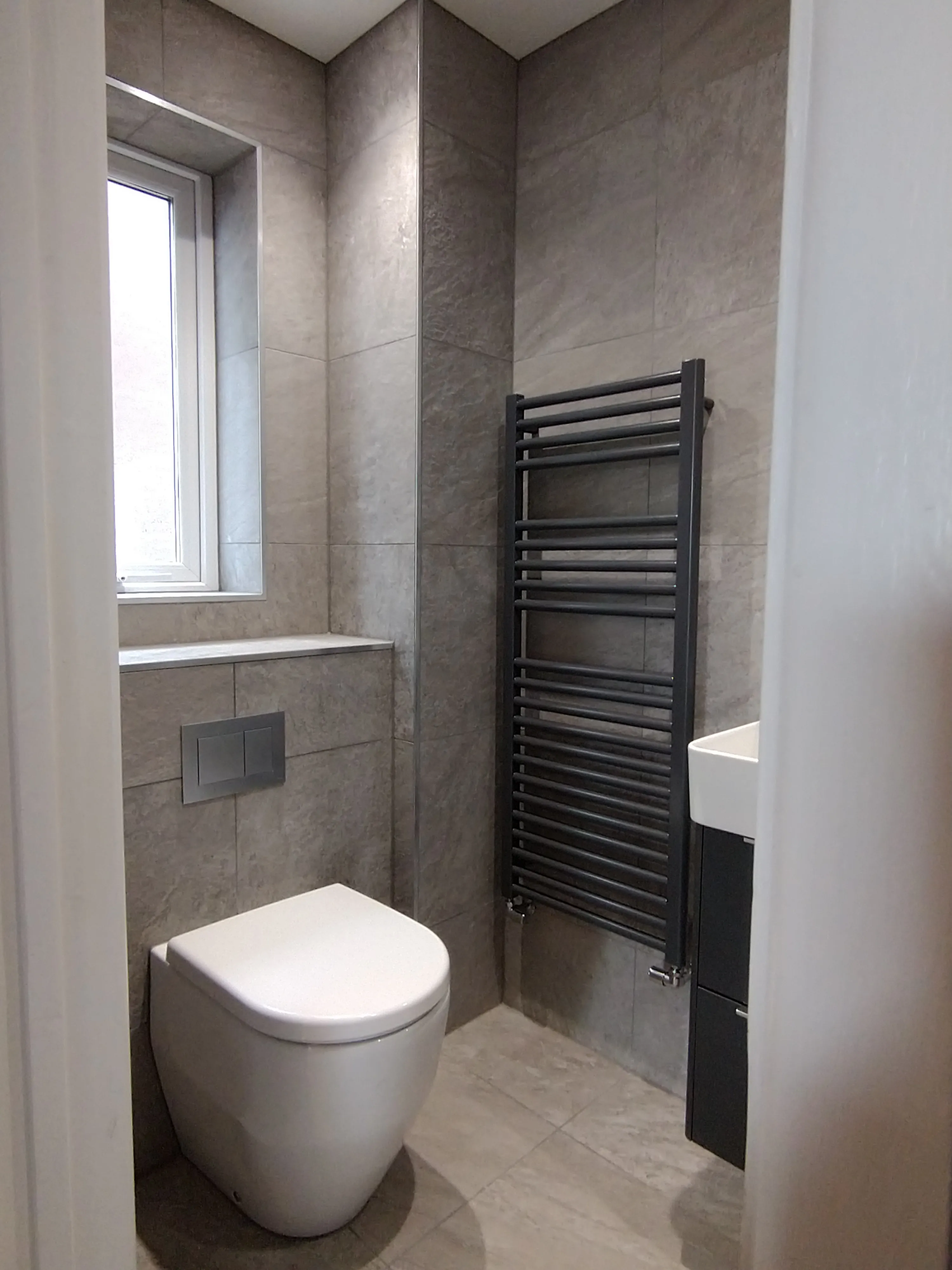 Luxury cloakroom installation in Plymouth featuring grey tiling and modern fixtures by Sands & Vossen.