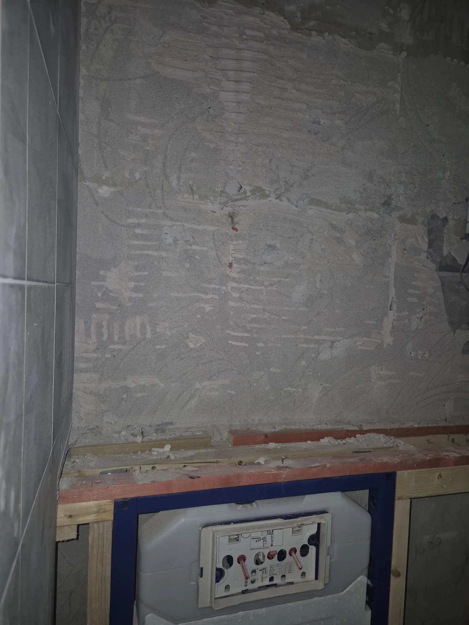 Bathroom renovation in progress with a wall-hung toilet frame and exposed wall.