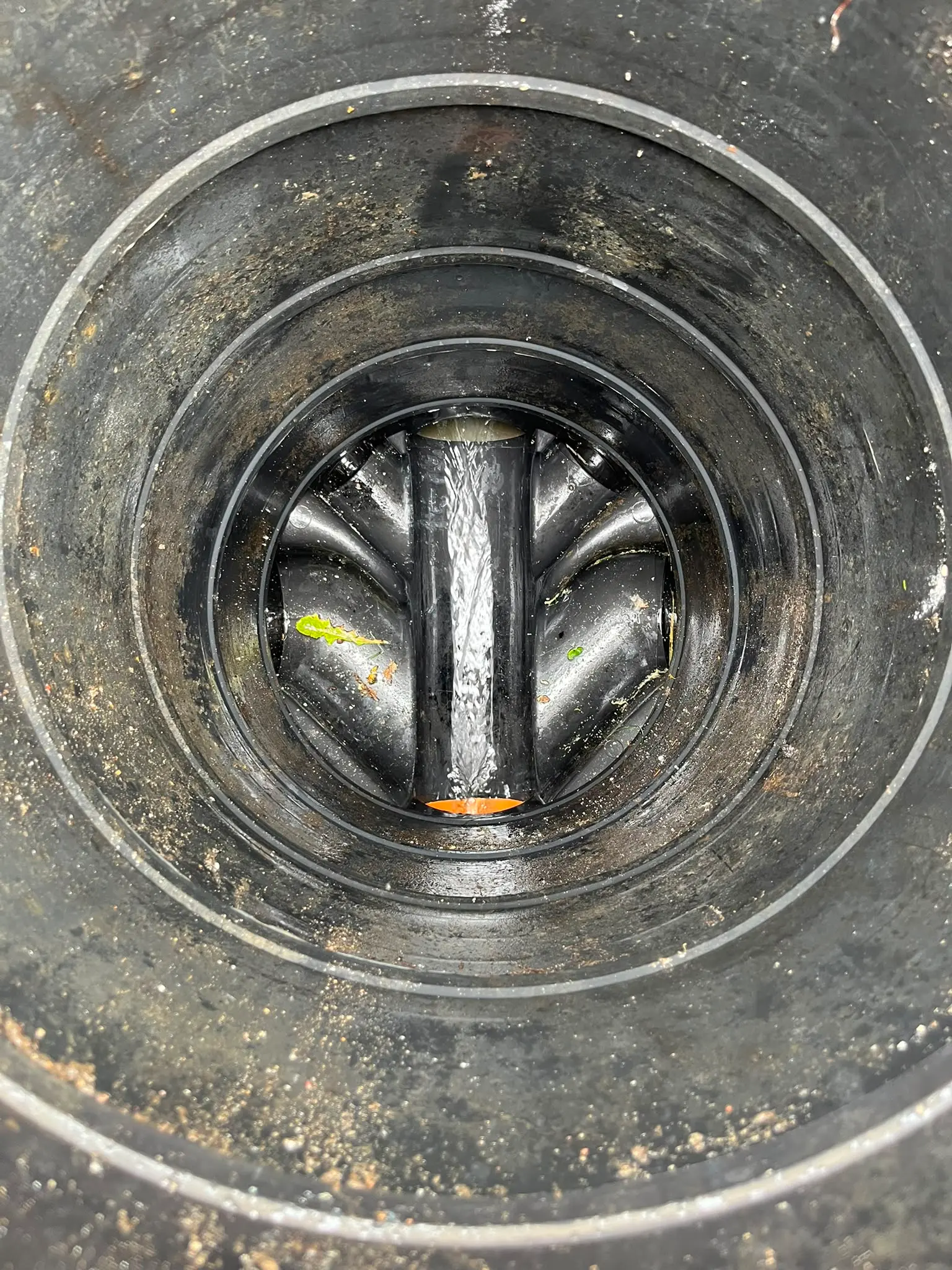 Inside a clean plastic drainage inspection chamber with water flowing freely, showcasing clear drains after professional manhole cleaning by CB Drainage.