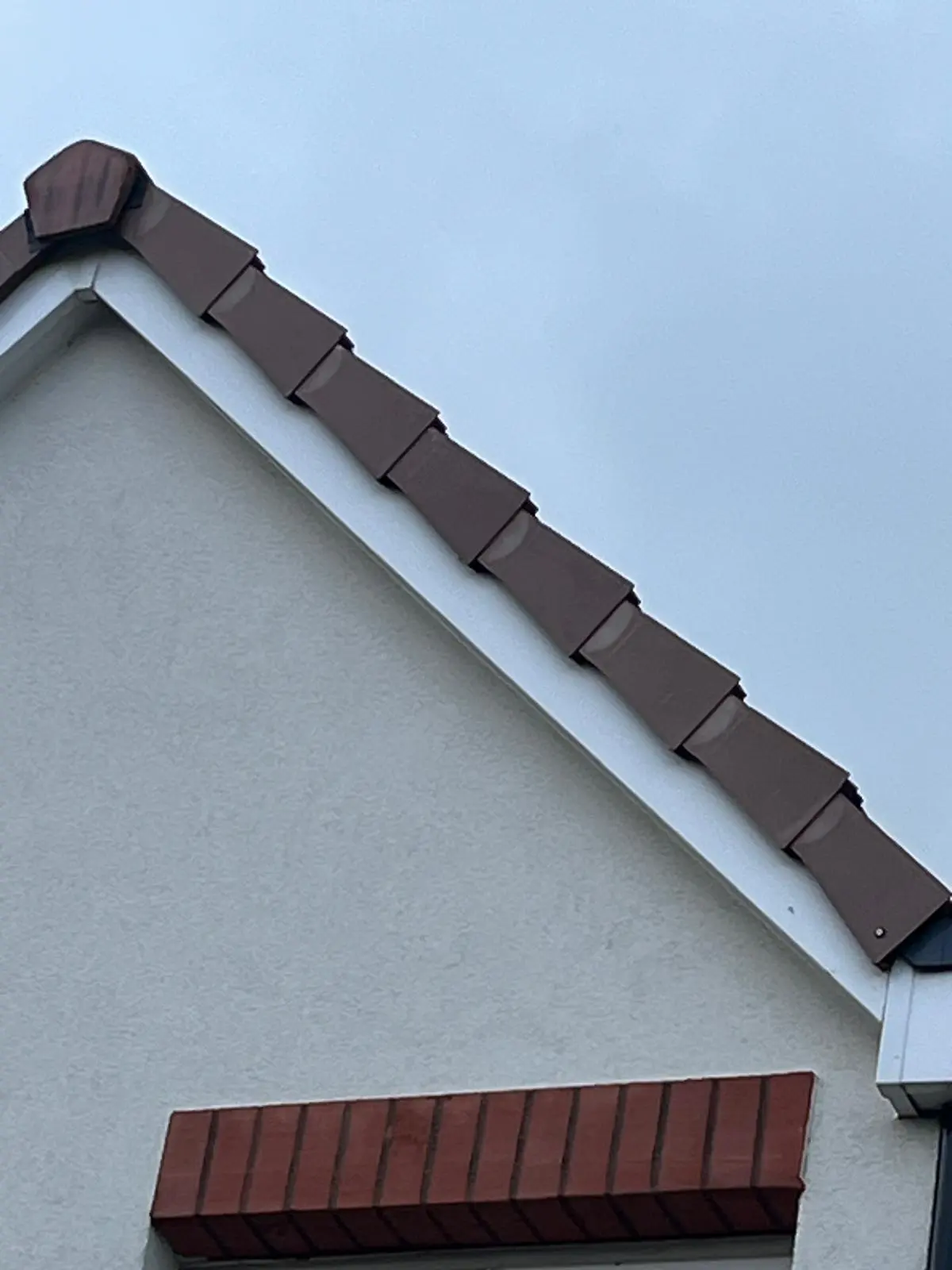 Brown uPVC dry verge system installed on the gable end of a tiled roof